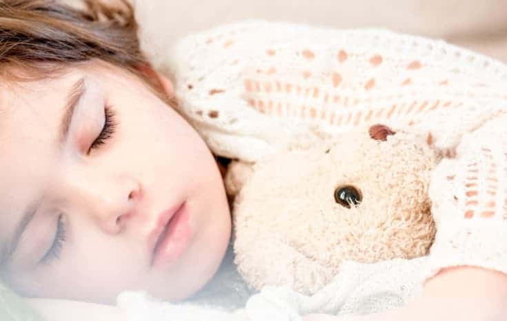 child sleeping with teddy bear, featured image for how to create a bedtime routine for kids that actually works